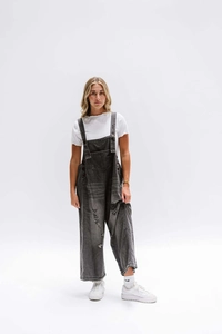 Detail of vintage grey distressed denim overalls with ripped design and wide-leg cut