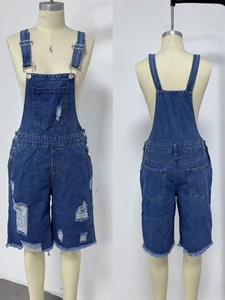Detailed view of women's denim overalls with distressed rips and frayed hem design