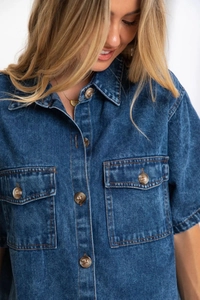 Dettaglio camicia di jeans blu scuro con colletto classico e bottoni marroni texturizzati