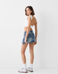 Vue latérale du haut court blanc dos nu et jupe en jean avec boucles métal utilitaires