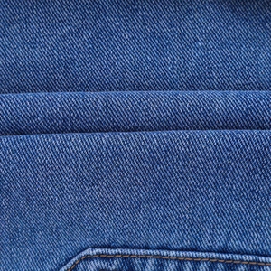 Détail macro du tissu denim bleu avec texture sergée et doubles surpiqûres marron