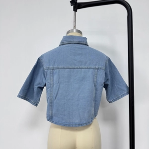Detail view of light blue denim short sleeve jacket with contrast stitching on torso