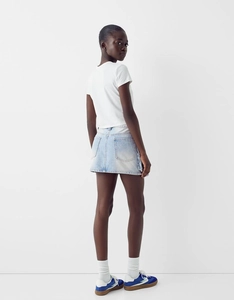 Détail d'une mini-jupe en jean avec poches arrière symétriques et une coupe trapèze légère