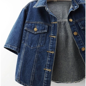 Close-up of deep blue short-sleeved denim jacket with bronze buttons and yellow stitching