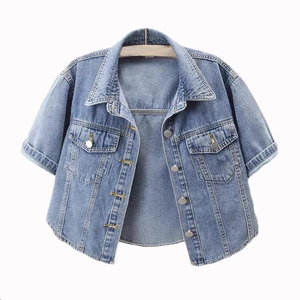 Detail of short-sleeved light blue denim jacket showing metal buttons and chest pockets
