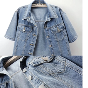 Close-up of light blue denim jacket texture with silver buttons and stitching detail