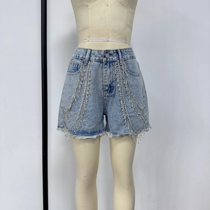 Detail of light blue denim shorts featuring sparkling rhinestone fringe and frayed edges