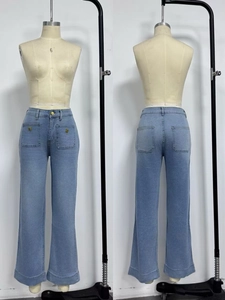 Detail view showing front gold button pockets and back pockets of light blue flared jeans