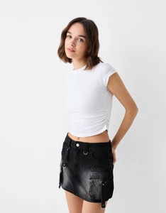 Détail d'une jupe cargo en denim noir avec de grandes poches et une boucle en métal stylée