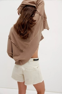 Detail view of off-white high waist denim shorts with frayed hems and cargo back pockets