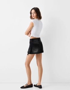 Détail de la mini-jupe en jean noir délavé avec poches cargo et coupe ajustée slim