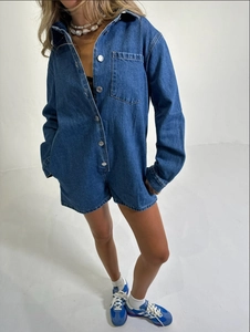 Détail d'une combinaison en jean ample avec col pointu et boutons-pression en métal