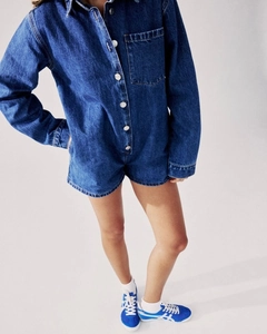 Détail d'un combishort en jean bleu foncé avec des boutons métalliques et une poche