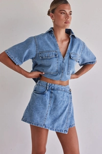 Detalle de conjunto cargo de mezclilla azul claro con bolsillos de solapa y minifalda cruzada
