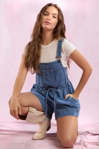 Detail of blue denim overall shorts with adjustable straps and waist drawstring