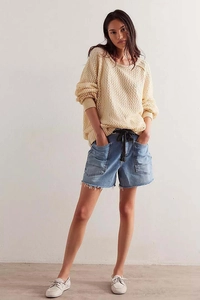 Detail of casual denim shorts with large patch pockets, drawstring waist and raw hem