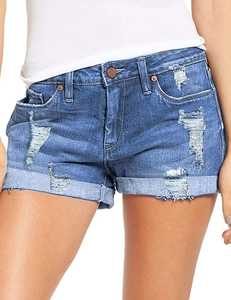 Detail of blue denim shorts showing distressed holes and rolled-up hem on white background