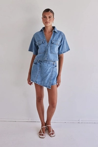 Detalle de conjunto de dos piezas en denim lavado claro con camisa cargo y minifalda cruzada