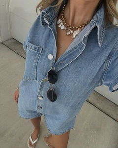 Détail du col en jean délavé bleu clair avec boutons argentés et collier de perles