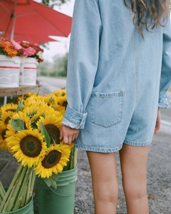 Vue arrière d'un combishort en jean bleu clair avec poches arrière en décor extérieur