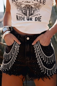 Detail of rhinestone fringe and shimmering crystals on black high-waist denim shorts