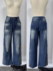 Détail du jean taille haute à jambe large avec broderies florales et déchirures usées