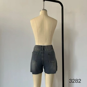 Detail of high-waisted washed black denim shorts featuring a raw hem design