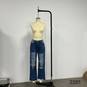 Detail of high-waisted distressed blue denim jeans with ripped knees and frayed edges