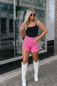 Detail view of pink denim shorts featuring sparkling rhinestone fringe and frayed hems