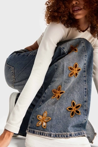 Détail de broderie florale et patchwork ajouré sur un jean denim ample à taille haute