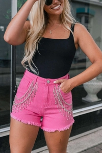 Detail of pink denim shorts featuring silver rhinestone fringe and frayed hem design