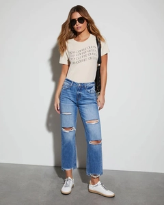 Detail of high-waisted distressed denim jeans with frayed knee holes and straight leg cut