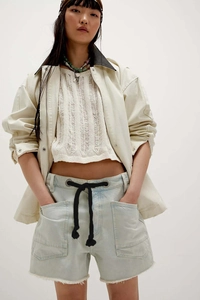 Detail view of casual frayed denim shorts with eyelet drawstrings and layered knit top