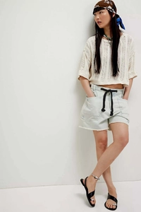 Detail of light blue washed denim shorts with frayed hems and black drawstring eyelets