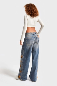 Détail arrière d'un jean taille haute à jambe large avec broderie florale et délavage clair