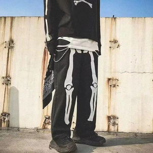 Detail of street-style black joggers featuring large white bone prints and a punk aesthetic
