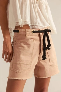 Detail of high-waisted peach denim shorts with large pockets and rope belt