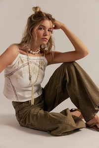 Detail view of a white lace-trimmed tank top paired with olive wide-leg bohemian trousers