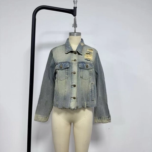 Detail of vintage blue denim jacket featuring distressed ripped texture and raw hem design