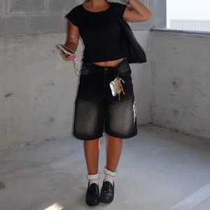 Φωτογραφία street style εξωτερικού χώρου με γυναικεία τζιν βερμούδα σε μαύρο ξεθωριασμένο