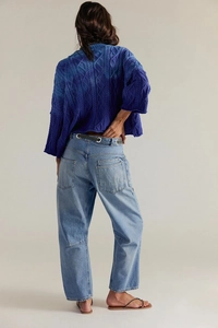 Détails de la maille du pull torsadé et poches arrière du jean large à taille haute