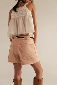 Detail of peach denim shorts with lace top and woven belt showing rear view