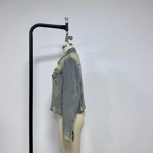 Detail of distressed light blue denim jacket featuring frayed edges and vintage wash