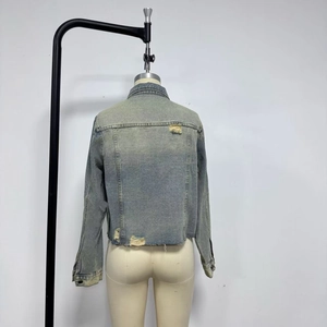 Detail view of the vintage washed denim jacket back featuring distressed ripped accents