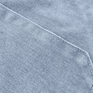 Macro shot of light gray denim texture with precise twill weave and sewing stitches