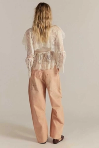 Détail du pantalon vintage américain avec taches de peinture et chemisier en dentelle