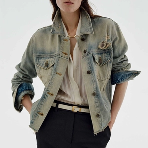 Close-up detail of vintage washed denim jacket showing distressed fabric and worn texture