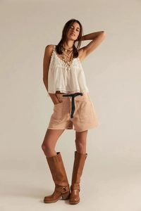 Detailed view of white lace patchwork camisole paired with peach frayed denim shorts