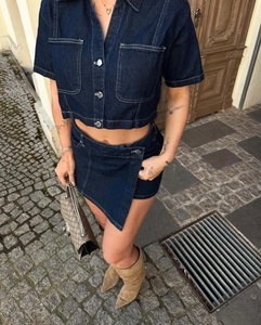 Close-up of deep blue denim two-piece set with button-up crop top and asymmetric skirt