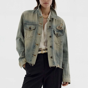 Close-up of vintage wash denim jacket featuring distressed details and raw edge hem
